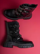 Botas negras de caña baja con suela track, cierre lateral y detalles de hebillas con tachas y cadenas.