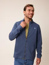 Buzo de cuello alto con cierre frontal completo, confeccionado en tejido de algodón y poliéster. Presenta un diseño liso en color azul melange con un pequeño logo bordado en el pecho y bolsillos laterales.