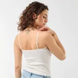 Camiseta de tirantes color blanco, con tejido de punto calado, detalles de encaje en el escote y tirantes finos regulables.