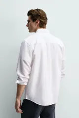 Camisa regular fit de manga larga con diseño a rayas verticales celestes y blancas. Cuenta con cuello abotonado, bolsillo de parche en el pecho y cierre frontal con botones.