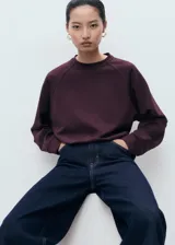 Buzo de cuello redondo y manga larga con diseño recto y holgado, confeccionado en tejido de punto suave.