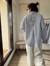 Camisa oversize a rayas verticales blancas y negras con bordado rojo en el frente.