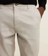 Pantalón slim de sastrería de color gris claro, confeccionado en sarga de algodón con elastano, con cierre frontal de botón y cremallera, y bolsillos.