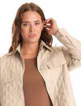 Chaqueta de eco cuero negro con diseño capitoneado, cuello con solapa y cierre frontal con botones a presión. Presenta mangas largas con puños abotonados, dos bolsillos frontales con solapa y forro interno a tono.