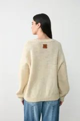Sweater de lana color crudo con diseño de la bandera de Uruguay tejido en el frente. Presenta un sol amarillo en relieve realizado en crochet y franjas horizontales azules. Posee cuello redondo acanalado y un corte holgado.