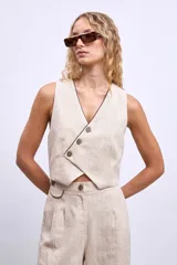 Chaleco color crudo con cuello en V y botones frontales.