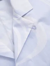 Camisa celeste con estampado de remolinos blancos, de corte recto, manga corta y cuello cubano.