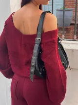 Sweater de punto color negro, con escote estilo bardot y mangas largas. Presenta un diseño acanalado y corte ajustado.