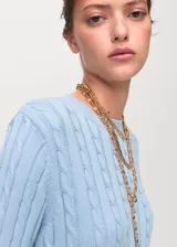 Jersey de punto trenzado en color celeste, con cuello redondo y manga larga, de diseño recto y corte clásico.