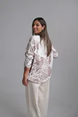 Sweter de punto con escote en V y mangas largas, presenta un diseño estampado abstracto en tonos tostado y blanco.