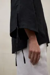 Blusa de lino blanca de corte amplio, con escote en V, mangas largas y puños con abertura y lazo.