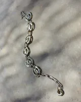 Pulsera de diseño artesanal elaborada eslabón por eslabón a mano, con eslabones circulares texturados de metal dorado y cadena regulable.