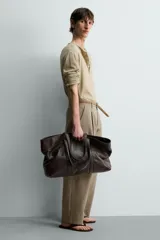 Bolso tipo shopper de piel en color negro, con diseño minimalista, doble asa de mano y compartimento principal con cierre magnético.