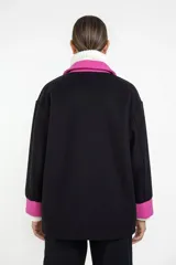 Sobre camisa de corte oversize en color negro con detalles en fucsia en cuello, bolsillos frontales y puños. Presenta cierre frontal con botones y diseño de dos tonos.