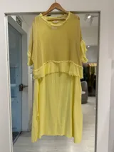 Vestido midi amarillo de corte recto, con superposición de tela de red en la parte superior y detalles de flecos en los bordes.