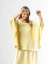 Sweater de tejido en red color amarillo mantequilla, con diseño oversize y amplio, mangas largas y caída holgada ideal para superposiciones.