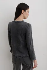 Remera de manga larga con efecto lavado, cuello redondo y estampa frontal con diseño de estrella y texto.