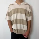 Chomba de tejido de punto con diseño de rayas horizontales anchas en tonos beige y crema, corte oversize, cuello polo y mangas cortas.
