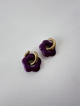 Aros de acero quirúrgico hipoalergénico con argolla dorada y dije en forma de flor color violeta.