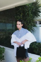 Blusa con cuello mao y mangas globo, confeccionada en algodón. La parte superior es de rayas azules y blancas, y la parte inferior es blanca con detalles de encaje.