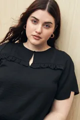 Blusa negra con textura, canesú con encaje, volados, corte fluido y mangas cortas amplias.