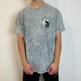 Remera de algodón con efecto lavado ácido en color gris, corte semi oversize y manga corta. Presenta un estampado gráfico en la espalda que muestra la silueta de Mickey Mouse sobre una luna blanca con el logo BY VCP.