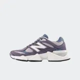 Championes New Balance modelo 9060, con diseño futurista inspirado en la era Y2K. Presenta una combinación de tonos violeta y gris, con detalles en blanco y una entresuela esculpida de gran volumen con tecnología de amortiguación ABZORB y SBS.