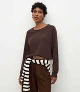 Suéter de punto color marrón chocolate, con cuello redondo y mangas largas con puños acanalados. Presenta un diseño básico y versátil de corte recto.