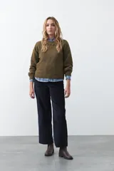 Sweater de tejido suave color tostado, con cuello redondo y detalle de flores bordadas en relieve en la parte superior del pecho. Presenta un corte relajado y mangas largas con puños ajustados.