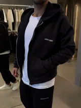 Campera con capucha y cierre frontal, de corte boxy y diseño holgado. Presenta logo bordado en el pecho y bolsillos tipo canguro.