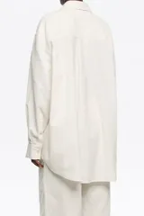 Camisa de corte recto en color blanco, con cuello clásico y cierre frontal de botones. Presenta mangas largas con puños abotonados y una textura sutil en el tejido.