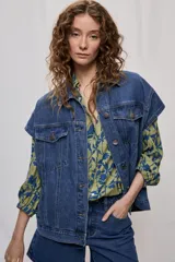 Chaleco de denim oversized en color azul, con cuello camisero, bolsillos delanteros con solapa y cierre frontal con botones metálicos.