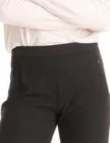 Pantalón de corte cigarette en color negro, de tiro medio-alto y largo tobillero. Confeccionado en tejido sastrero antiarrugas, presenta una silueta entallada, bolsillos delanteros con cierre metálico simulados y bolsillos traseros tipo ojal simulados.