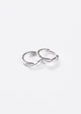 Par de aros tipo argolla pequeños de plata 925, con diseño trenzado o retorcido incrustado con pequeñas circonias brillantes.