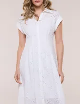 Vestido midi blanco estilo camisero de la marca Julia Jordan, confeccionado en tejido broderie 100% algodón. Presenta cuello camisero tradicional, cierre frontal con botones, mangas cortas con vuelta y cintura entallada con pinzas que da paso a una falda evasé. Cuenta con forro interior.