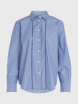 Camisa de manga larga a rayas verticales azules y blancas, con cuello inglés y corte amplio. Presenta detalles distintivos de la marca Tommy Hilfiger y logo bordado en el puño.