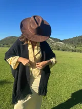 Ruana de lana merino en color tostado, con diseño de punto texturizado y terminación de flecos en el ruedo.