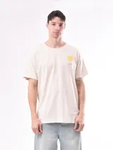 Remera de manga corta color beige claro, con cuello redondo y un pequeño estampado de un sol amarillo con texto en el pecho.
