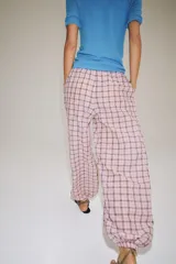 Pantalón bombacho de tiro medio, confeccionado en mezcla de algodón con estampado de cuadros en tonos rosados y oscuros. Presenta cintura elástica y bajo abullonado con puño elástico.