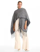 Ruana de tejido tweed en tonos verdes con destellos de lurex, diseño abierto con terminación de flecos en los bordes.