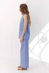 Chaleco largo color blanco con rayas verticales finas color beige, con cuello en V y cierre frontal con botones marrones. Incluye pañuelo al cuello con estampado de lunares y rayas.