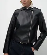 Campera estilo biker de poliuretano, con cierre frontal asimétrico, cuello con solapas y cremalleras en los puños. Presenta un diseño entallado con acabado liso.