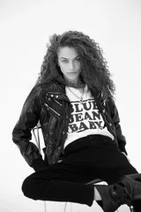 Campera negra estilo motociclista, con cierre frontal asimétrico, múltiples cierres decorativos y cuello con broches.