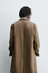 Abrigo de corte regular fit confeccionado en tejido compacto con mezcla de lana. Presenta cuello con solapas de muesca, cierre frontal de botonadura, bolsillos de vivo en la cadera y abertura central en la espalda.