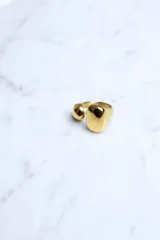 Anillo abierto de metal dorado con diseño orgánico y acabado brillante.