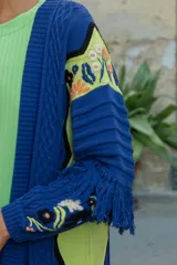 Sacón azul de algodón y acrílico con bordados de motivos tropicales en frente, espalda y mangas, y flecos en las mangas.