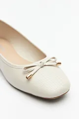 Balerinas negras de símil cuero texturizado con aplique de moña y detalles metálicos.