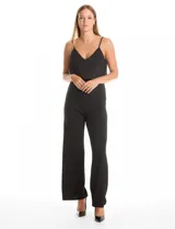 Enterito de crepe negro con diseño de capa suelta en el torso, escote en V y breteles finos ajustables. Presenta cintura definida y pantalón de pierna ancha con caída fluida, con cierre invisible en la espalda.
