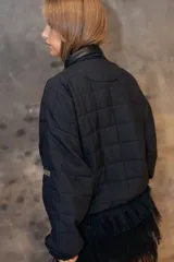 Campera puffer de diseño matelaseado en rombos, color beige. Presenta cuello alto, cierre frontal y solapa triangular decorativa con logo bordado. Posee mangas largas con puños elastizados y ruedo ajustado tipo bomber.