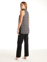 Blusa sin mangas de gasa estampada en tonos negros, grises y blancos, con escote en V pronunciado, pliegues en los hombros y ruedo asimétrico con tajos laterales.